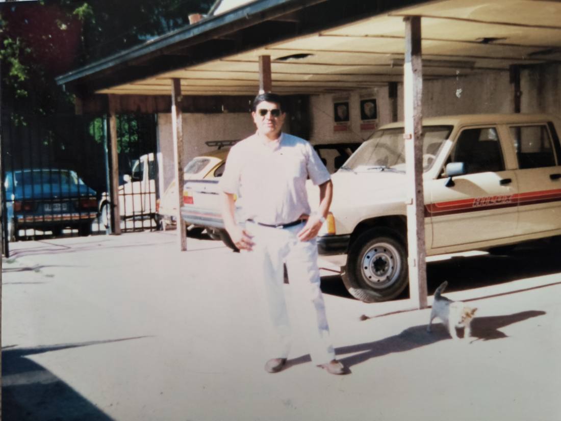 Fotografía antigua del patio techado del local, con una camioneta y otros vehículos en venta.